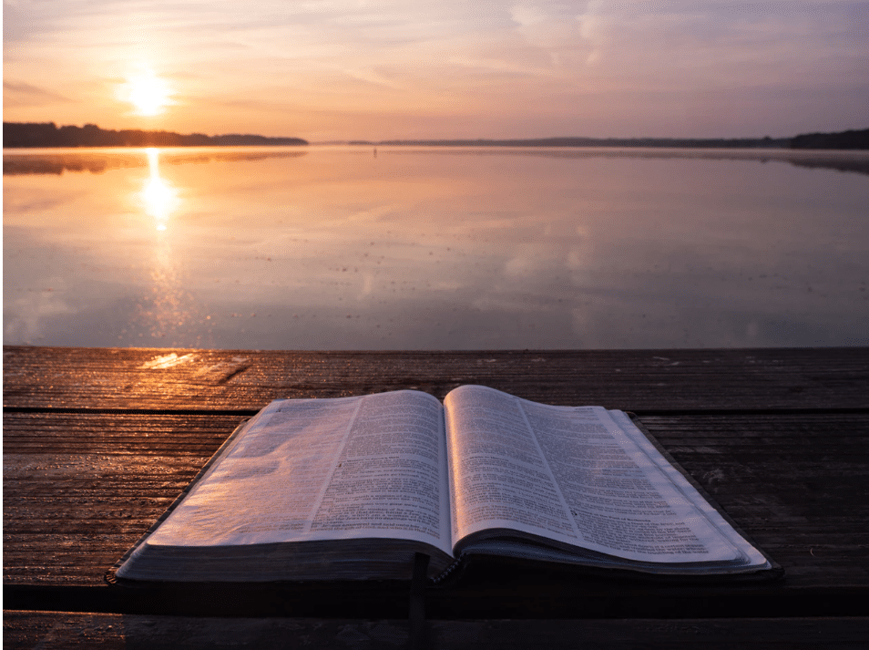 bible in front of lake view with sunset