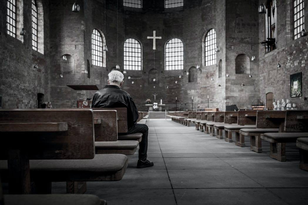 man sitting in empty church building with no lights